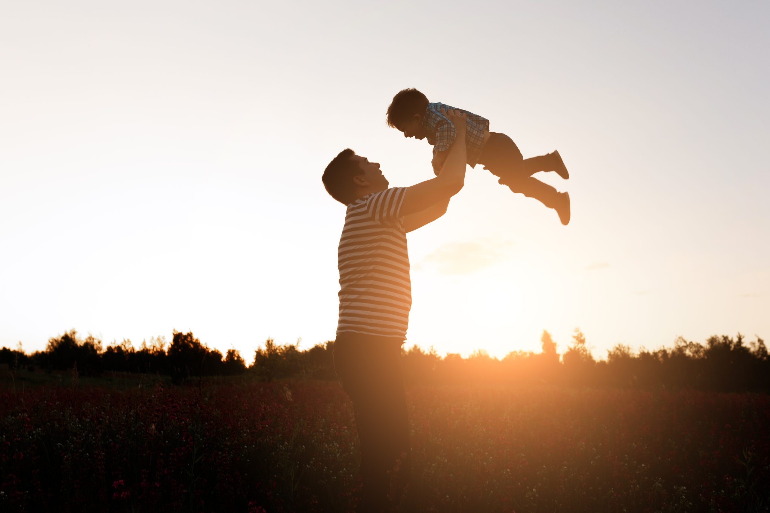 Father and son playing in the park at the sunset time. Happy family having fun outdoor.